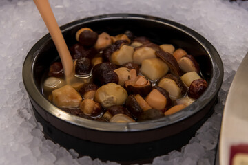 Colorful bowls of gourmet mushrooms are arranged neatly on ice, making a tempting display at a food market event. Copy space. Soft focus.