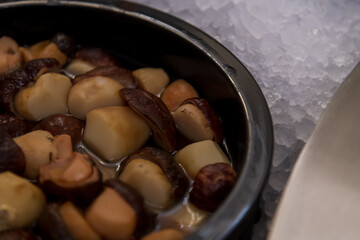 Colorful bowls of gourmet mushrooms are arranged neatly on ice, making a tempting display at a food market event. Copy space. Soft focus.