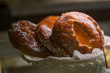 Delicious pastries sit in a glass case at a local bakery, their golden-brown crust gleaming under soft lighting as customers browse in the afternoon.
