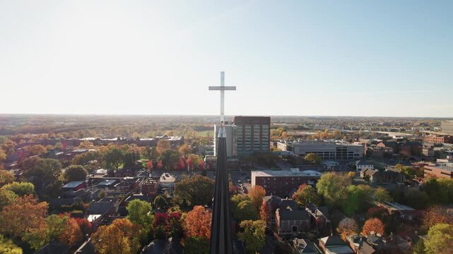 Catholic Jesus cross and religious symbol of Christianity, Lutheran, and Catholicism from a drone shot above vintage church steeple and tower as aerial close up and macro shot moves around crucifix