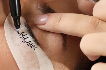 Esthetician mapping under eye patch before lash extensions procedure, closeup