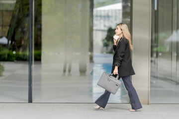 Confident businesswoman walking through a modern urban environment with reflective glass buildings,...