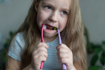 Caucasian young girl playfully holding two toothbrushes in mouth