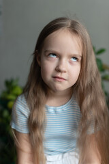 Caucasian female child with long hair making a playful expression indoors