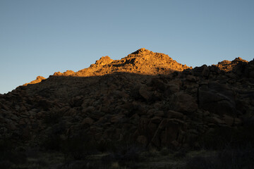 Top Of Rocky Hill Side Is Warmed By Late Day Sunlight