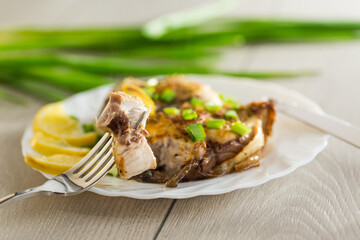 Homemade fish dish with lemon and herbs in a plate on a wooden table