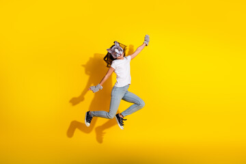Thematic portrait of a young girl jumping energetically in a cat-inspired costume on a vibrant yellow background
