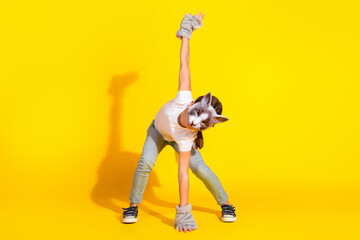 Young girl wearing a playful animal mask doing a fun stretch in bright yellow background