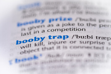 Booby trap word in a dictionary. Selective focus, close up.