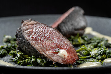 This gourmet dish features grilled meat on fresh spinach with a rich, flavorful sauce