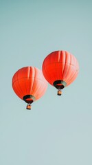 Fototapeta premium Two vibrant hot air balloons ascend into a clear blue sky during a serene morning flight in a picturesque setting