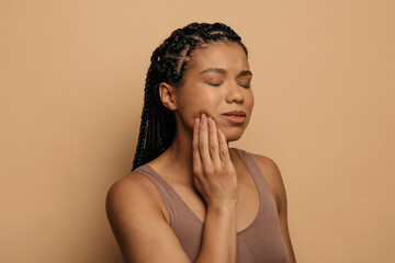 Teeth problem. African woman suffering from acute toothache, touching chin and frowning, having...