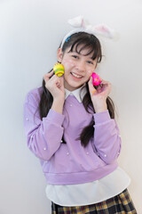 Isolated girl wearing bunny ears holds colorful Easter eggs during spring celebration on white background