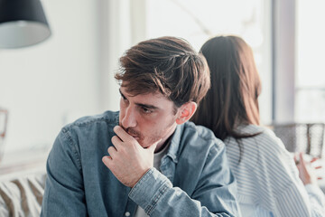 Beautiful lady is depressed, sitting on the couch talking to man, having a dispute with husband or...