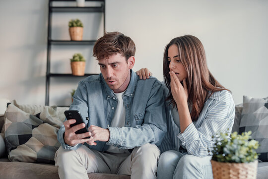 Shocked caucasian man and woman looking at phone close up, unhappy couple receive bad news in email, debt notification from bank, loosing money in mobile app, problem with broken cellphone.