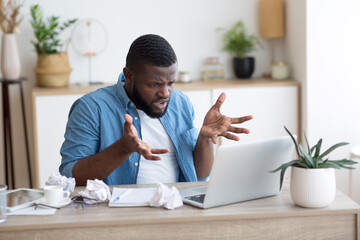 Portrait of serious african male business manager having web call via computer, sitting at workplace in office, talking and gesturing at computer screen, discussing work problems. High quality photo