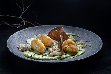 Savor gourmet potato gnocchi with creamy avocado sauce and crispy chips for texture
