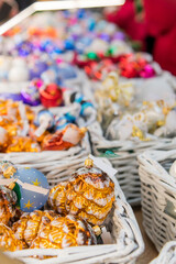Colorful handmade ornaments displayed in woven baskets at a festive market during the holiday season