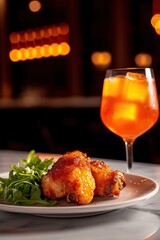 A plate of glazed chicken wings served with a side of fresh greens and a vibrant orange drink, all under warm ambient lighting.