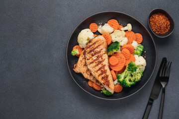 Grilled chicken breast and broccoli, cauliflower and carrots. Chicken meat with vegetables. Healthy food. Dark background top view