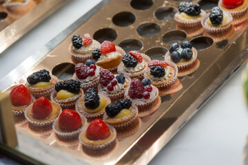Delicious assortment of fruit-topped pastries displayed at an elegant dessert table during a festive event