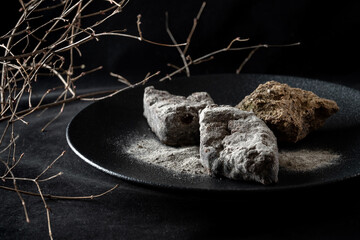 An exquisite and artistic dessert presentation featuring elegant chocolate and fine powdered sugar. Decorated with natural stones.