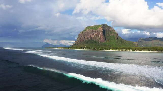 Blue water ocean waves waving over coral reefs next to Le Morne peninsula with basalt mount on Mauritius island. Also a wonderful kiteboarding and windsurfing spot. Exotic traveling aerial 4K video.