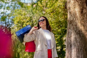 mulher de 50 anos com sacolas de compras posando ao ar livre em dia de verão