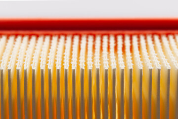 A close-up shows the air filter's intricate white fibers packed between orange folds, highlighting...