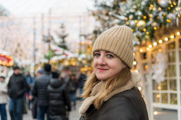 Fototapeta premium Woman in winter attire enjoying a festive market atmosphere during the holiday season in a city adorned with lights