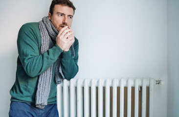 Man feeling cold at home with home heating trouble