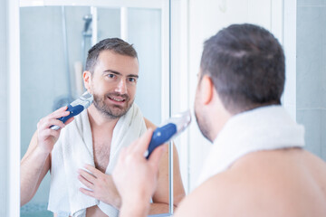 Fototapeta premium One man trimming his beard using electric beard trimmer