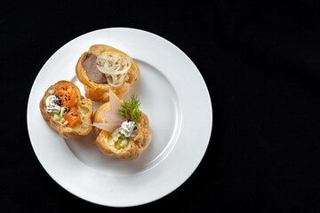Indulge in gourmet, Asianinspired bites beautifully presented on an elegant plate. Delicious profiteroles filled with fish, pate, onions. Plated on a white plate.