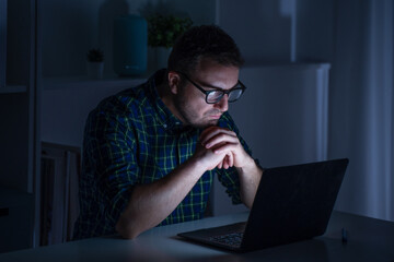 One man working late at night on computer worried