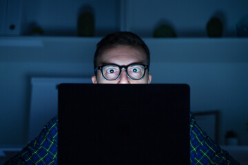 Computer nerd portrait using computer late at night