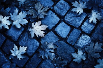 Dried autumn leaves scattered on a dark blue cobblestone pavement.