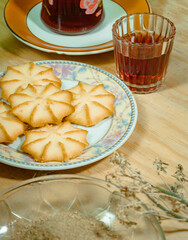 Butter and salt cookies on plates on a wooden base with red tea and seasonings