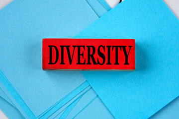 DIVERSITY - word on a red wooden block on a blue background of papers