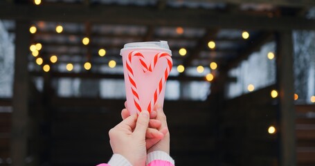 Gentle scene merges pink beverage and candy cane heart, reflecting warmth in subtle lights, as...