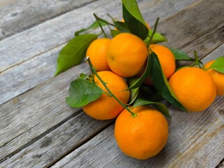 Juicy ripe tangerines with green leaves on a wooden table