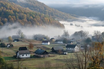 Fog envelops a tranquil village nestled in the mountains during early morning light