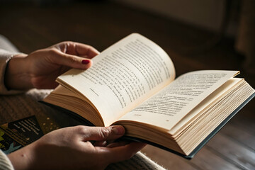 Naklejka premium A person holds an open book, displaying multiple pages, with a cozy setting that suggests reading and relaxation.