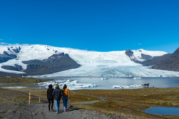 Fototapeta premium Tourists walking towards Fjallsarlon Lagoon with Vatnajokull Glacier in background