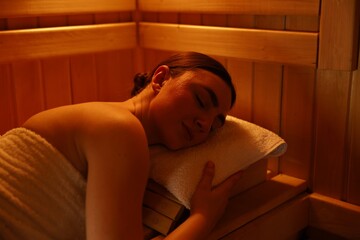 Beautiful woman lying on bench in sauna
