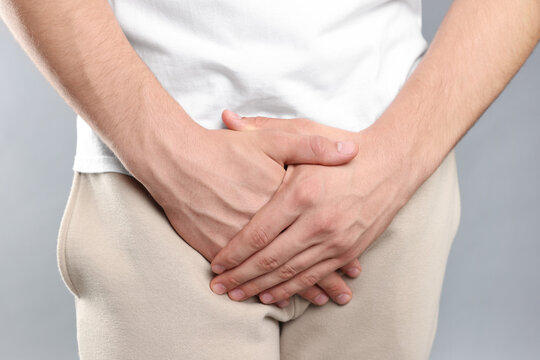 STD (sexually transmitted diseases). Man suffering from symptoms on grey background, closeup