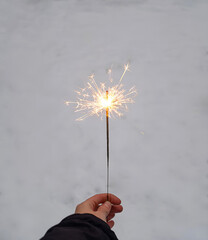 Woman holding sparkler in her hand on a snow background. SPARKLING BENGAL LIGHT