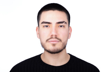Strong eye contact portrait of a young man with a neutral expression, wearing a black high-collar shirt, looking straight into the camera.
