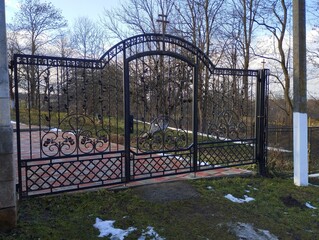 Metal wrought iron gate at the entrance. Entrance gate made of black metal with a small gate in the middle.