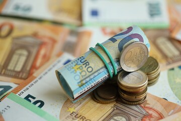 Roll of euro currency money bills and many euro cents on banknotes of european union