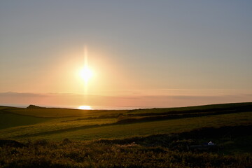 beautiful yellow sunset, Cornwall coast photo looking out across grassland to the ocean